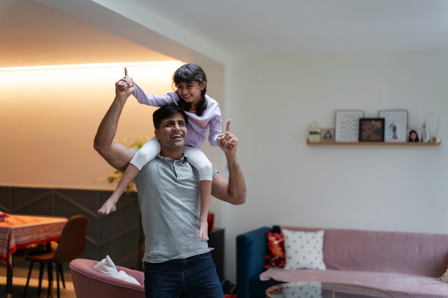 Father carrying daughter on shoulders at home
