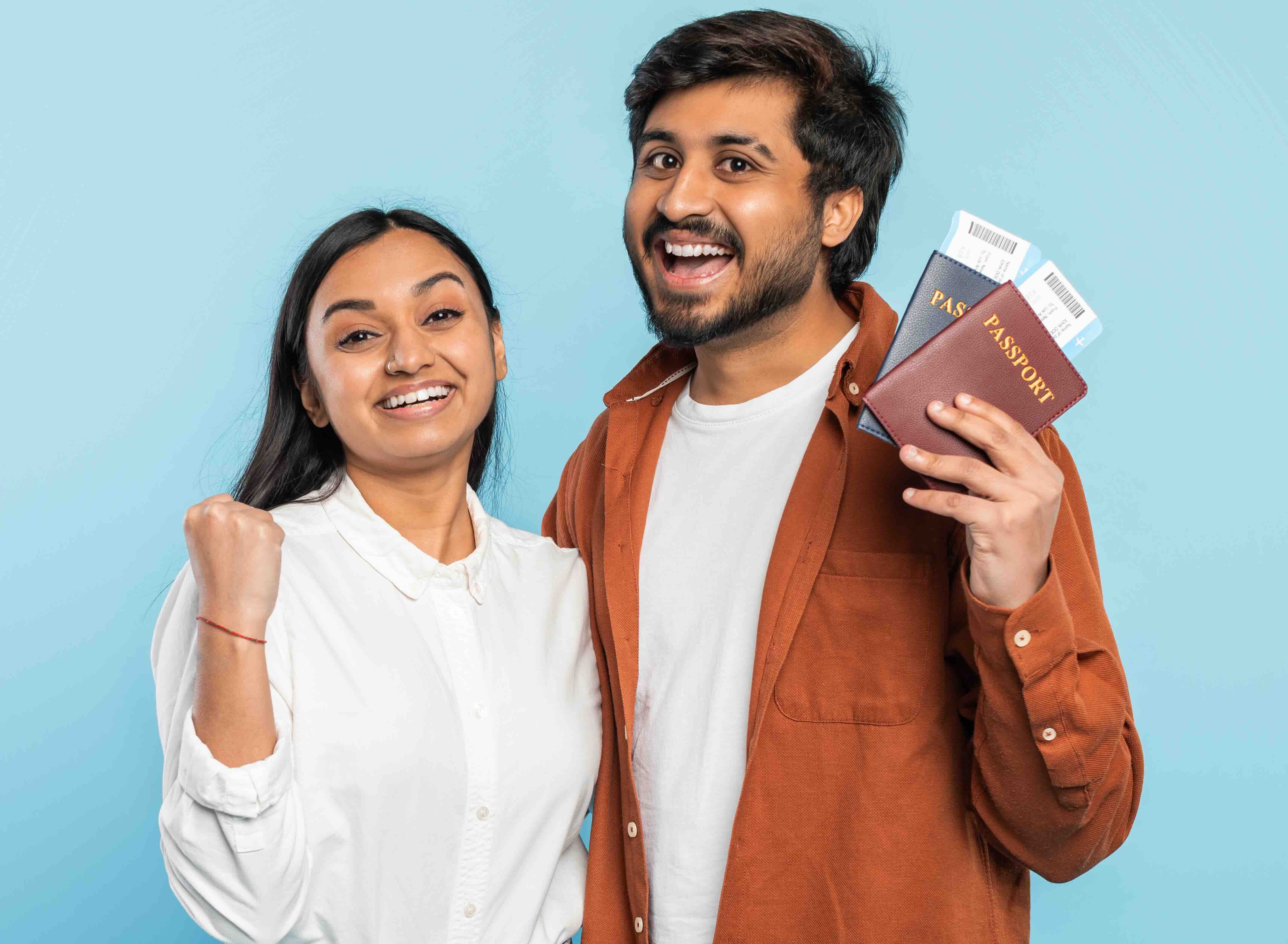 Excited couple with passports looking hopeful on blue