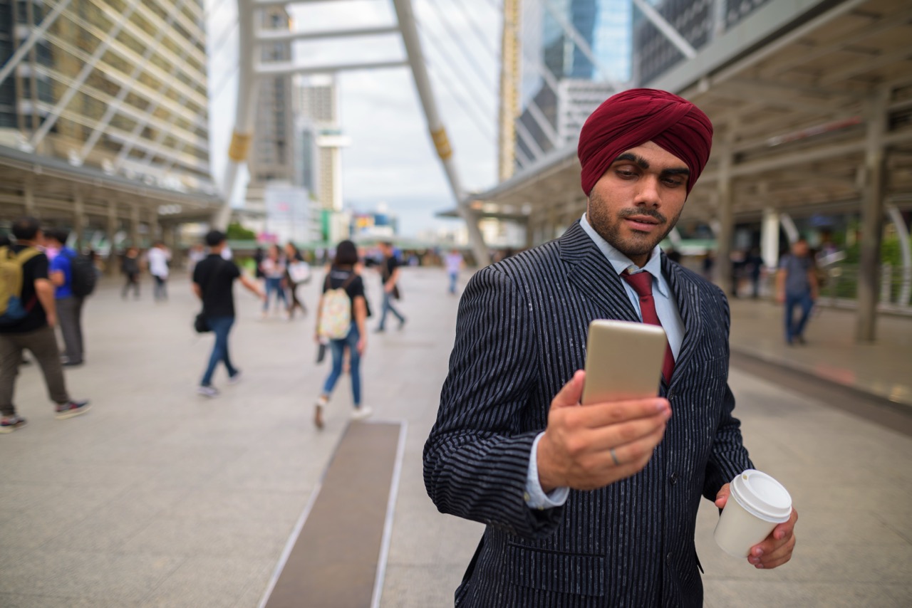 Indian businessman outdoors in city using mobile phone